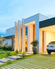 a modern house with grass and plants in the front yard