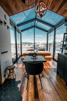 a dining room with wooden flooring and large windows overlooking the mountains in the distance