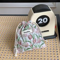 a small white bag sitting on top of a table next to a black and white clock