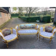 three white and gold couches sitting next to each other on a brick walkway in front of a house