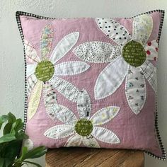 a pink pillow sitting on top of a wooden stool next to a potted plant