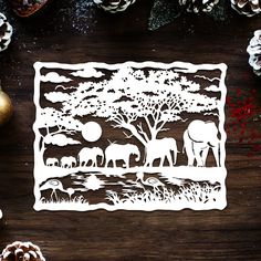 the paper cut art is displayed on a table with pine cones and other holiday decorations