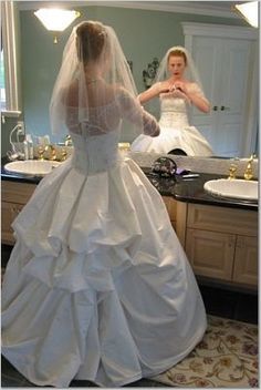 a woman in a wedding dress looking at herself in the mirror