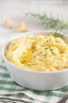 a white bowl filled with mashed potatoes on top of a green and white checkered napkin