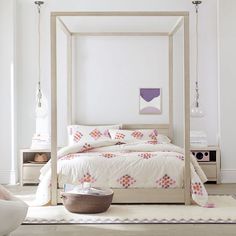 a bedroom with a canopy bed, white walls and rugs on the floor in front of it