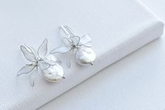 The Edith bridal earrings are the perfect finishing touch to your wedding day look. The shimmering pearls and artful butterfly details create an enchanting, feminine aesthetic that will have all eyes on you as you walk down the aisle. These earrings are designed to elevate your bridal ensemble, ensuring you feel beautiful, confident, and picture-perfect on your special day. DETAILS ❁Handcrafted dip resin butterflies with shinny and translucent details. ❁Elegant design and dainty outline with shi Delicate Flower-shaped Pearl Earrings For Wedding, Pearl Flower-shaped Wedding Earrings, Flat Pearl Earrings, Elegant Flower-shaped Pearl Drop Earrings, Formal Flower-shaped Bridal Earrings With Pearl Drop, Pearl Butterfly Earrings, Feminine Aesthetic, Butterfly Earrings, Wedding Jewelry Earrings