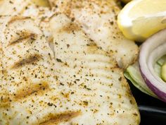 a close up of some chicken on a plate with lemons and cucumbers