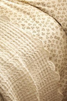 an unmade bed with white sheets and brown flowers on the comforter is shown