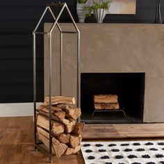 a fireplace with logs stacked in front of it and a rug on the floor next to it