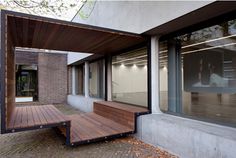 a wooden bench sitting in front of a window next to a brick building with large windows