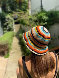 a woman wearing a multicolored knitted hat looking down at the ground outside