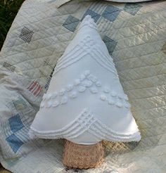 a small white christmas tree sitting on top of a quilted blanket next to a plate