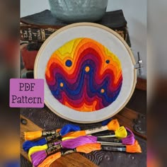 an embroidery project with different colors and designs on it, next to some crochet hooks