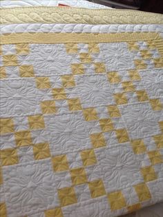 a yellow and white quilt sitting on top of a bed