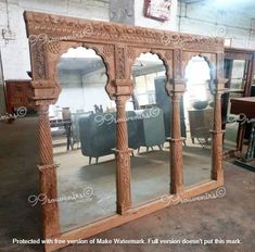 a large wooden mirror sitting on top of a floor next to a table and chairs