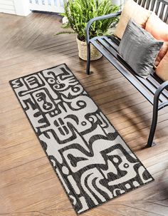 a black and white rug sitting on top of a wooden floor next to a bench