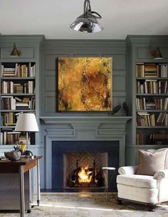 a room with a fireplace, bookshelves and pictures on the wall above it