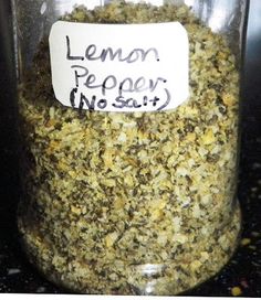 a jar filled with lemon pepper seasoning sitting on top of a counter next to a sign that reads lemon pepper no salt