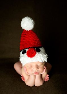 a baby wearing a santa hat laying on its back