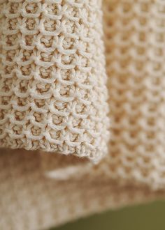 two knitted towels hanging from a hook on a clothes line, close up view