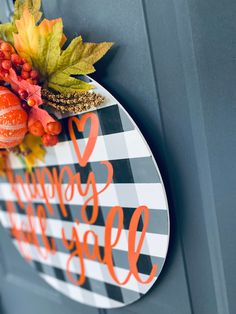 a happy fall door hanger on the side of a house with pumpkins and leaves