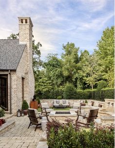 an outdoor living area with chairs, tables and fire pit in the middle of it