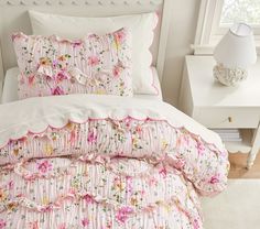 a white bed with pink and yellow flowers on it