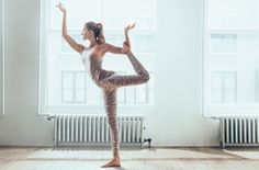 a woman is doing yoga in front of a window with her hands up to the side