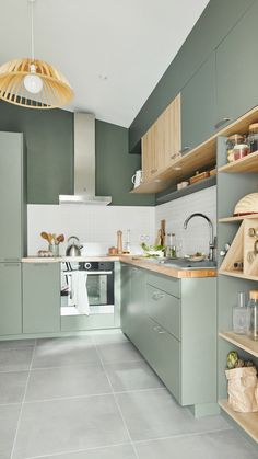 a kitchen filled with lots of green cabinets and counter top space next to a sink