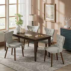 a dining room table with four chairs and a rug on the floor in front of it