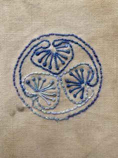 an embroidered design on the side of a piece of cloth with blue thread and stitching