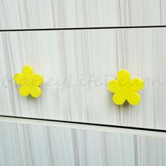 two yellow flowers are on the side of a white cabinet