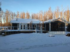 a house with snow on the ground and trees in the background