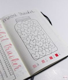 an open notebook with some writing on it and a jar of hearts in the middle