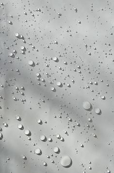 drops of water on the surface of a window with grey sky in the back ground