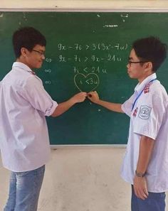 two young men standing in front of a blackboard