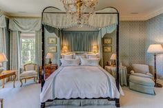 a bedroom with a four poster bed, chandelier and two lamps on either side of the bed