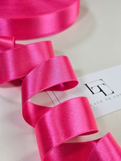 a pink ribbon is laying on top of a white table