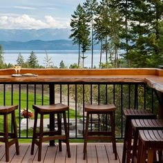 three wooden stools sitting on top of a wooden deck next to a table and chairs