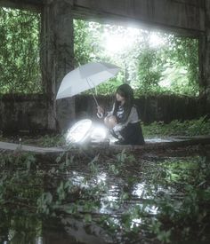 a woman sitting on the ground holding an umbrella