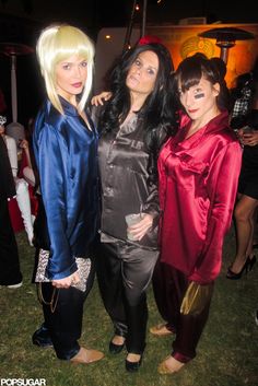 three women dressed in costumes standing next to each other on the grass at a party