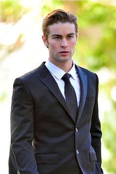 a man in a suit and tie is standing outside with his hands in his pockets