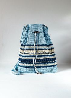 a blue crocheted bag sitting on top of a white floor next to a wall