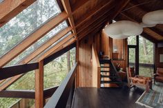 a living room with wooden walls and flooring next to a stair case in front of a window