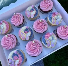 a box filled with lots of pink and blue cupcakes