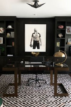 a black and white room with an art work on the wall above it, along with a desk