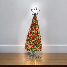 a christmas tree made out of beads on top of a wooden table next to a white wall