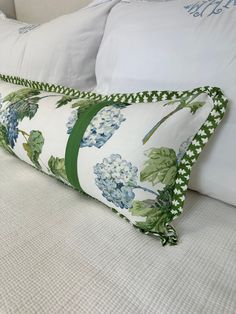 a close up of a pillow on a bed with white pillows and green trimmings