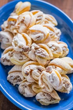 a blue plate topped with powdered sugar covered pastries on top of a wooden table