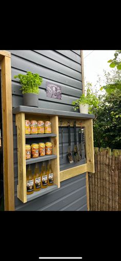 a wooden shelf filled with jars and spices next to a fenced in garden area